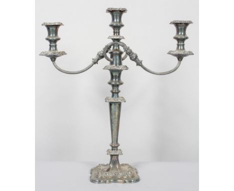 A silver plated Victorian three light candelabra, cast with rocaille scroll sconces with urn shaped nozzles and reeded branch