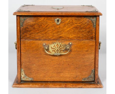 A Victorian oak tobacco cabinet, mounted with brass trefoil corner bracket, escutcheons and handles, the hinged cover reveali