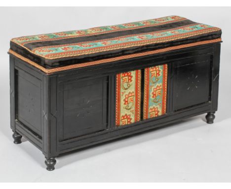 A Victorian ebonised ottoman-chest, of low rectangular section, with square recessed panelled front, back and sides, carved w