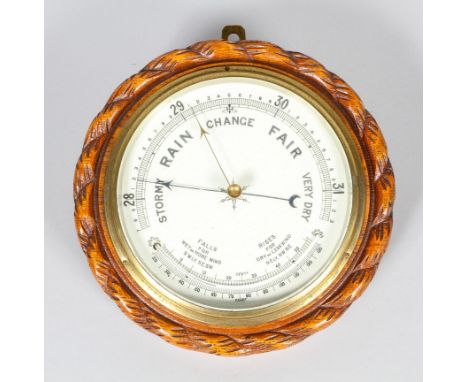 An early 20th century oak cased barometer, with white enamelled dial, with carved ropetwist rim27 cm. diam. 