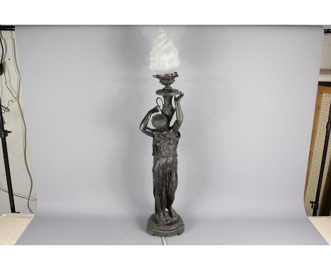 A spelter floor lamp; the lamp depicting a classical figure holding an urn lamp on her shoulder approx 95 cms h.&nbsp;