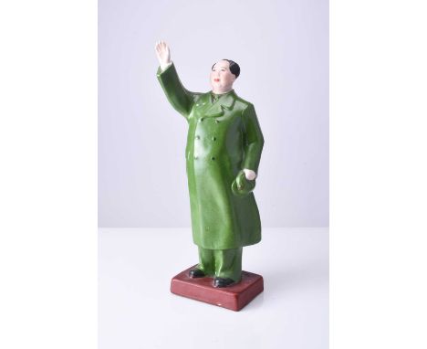 A Chinese propaganda porcelain figure of Mao Tse TungModelled standing with right hand raised, he wears a long green overcoat