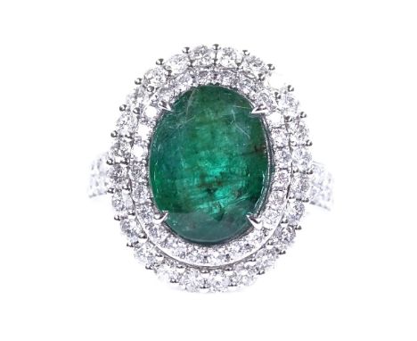 An 18ct white gold emerald and diamond cluster cocktail ring, with diamond set shoulders, oval-cut emerald approx 3.7ct, tota