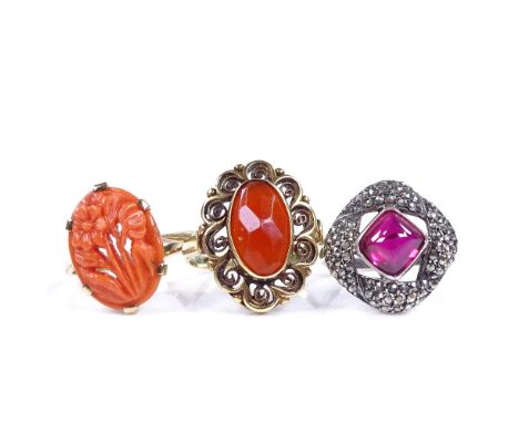 A 14ct gold carnelian dress ring, size M, a 9ct carved coral panel ring, size M, and a silver cabochon ruby and marcasite rin