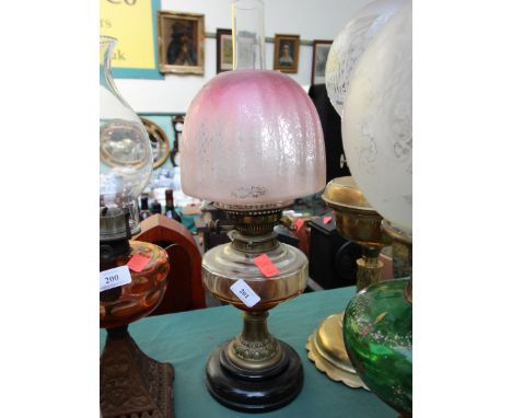 Brass and glass oil lamp on wooden base with pink glass shade and funnel