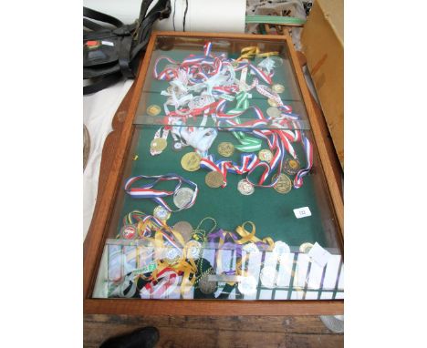 Glass fronted oak display cabinet containing a collection of athletics and other badges