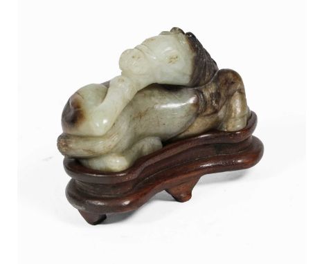 A Chinese Celadon and Russet Jade Horse, Ming Dynasty, worked recumbent on its side, 6cm long, on a later hardwood standCondi