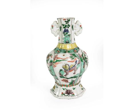 A Chinese Porcelain Vase, Kangxi, of fluted oval baluster form with twin scroll handles, painted in famille verte enamels wit