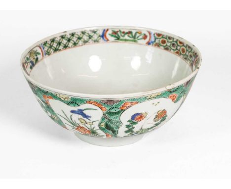 A Chinese Porcelain Bowl, Kangxi, painted in famille verte enamels with flowering branches in asymmetrical panels, on a green