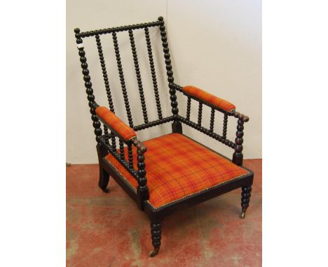 Victorian ebonised bobbin armchair, the arm rests and seat upholstered in later tartan stuff-over fabric, on brass castors, 9