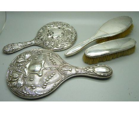 A silver backed Art Nouveau hand mirror, Birmingham 1906, one other mirror, a/f, and two silver backed brushes 