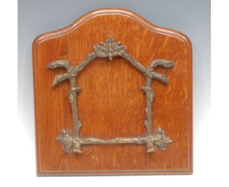 A late Victorian bronze and oak wall mounted newspaper or periodical rack, the folding bracket cast with acorn laden branches