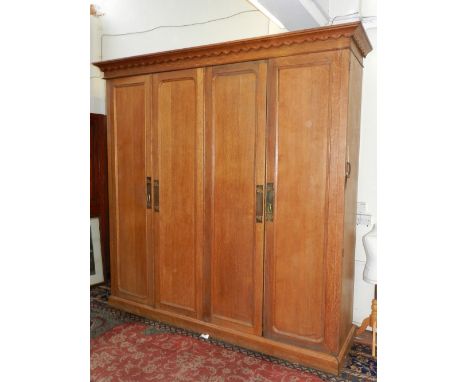 An impressively large Victorian oak wardrobe, the carved cornice above an arrangement of four panel doors enclosing hanging s