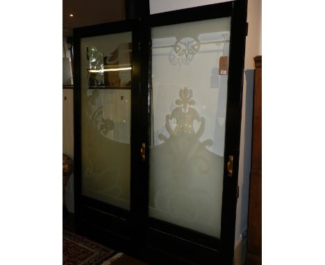 Three etched glass panel doors forming a screen, the foliate panels within black painted frames with brass fittings, 202 x 63