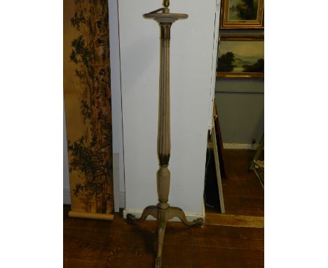 A wooden torchere-style floor lamp, painted cream and gold, having fluted stem and a tripod base with claw and ball feet.