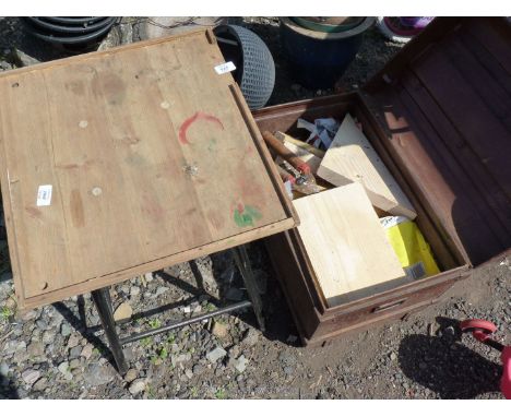 A metal trunk and contents and a wooden table.