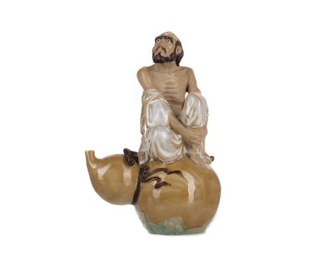 CHINESE POTTERY FIGURE,modelled as an ascetic monk sat with walking stick on a double gourd, 26cm high