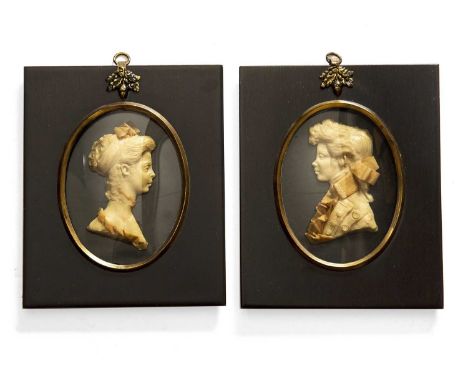 A pair of wax or plaster silhouette portrait miniatures of a young man and woman, both formally dressed in black frames with 