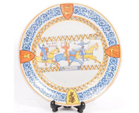 A ceramic / glazed wall plaque / plate depicting a scene from the battle of Hastings.&nbsp; Front of plate is embellished wit