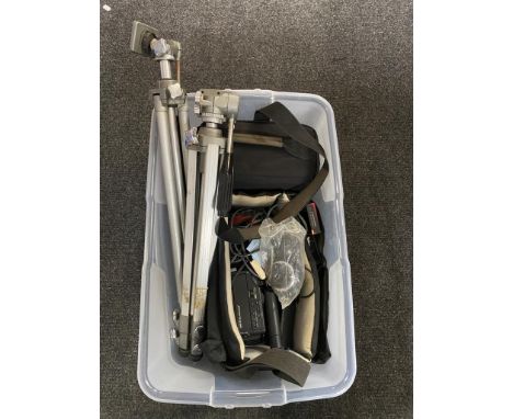 A clear plastic storage crate with lid containing camera tripods and two camcorders in carry bags 