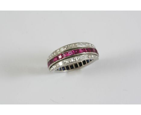 A SAPPHIRE, RUBY AND DIAMOND SWIVEL ETERNITY RING set with calibre-cut sapphires and rubies and square-shaped diamonds, in wh