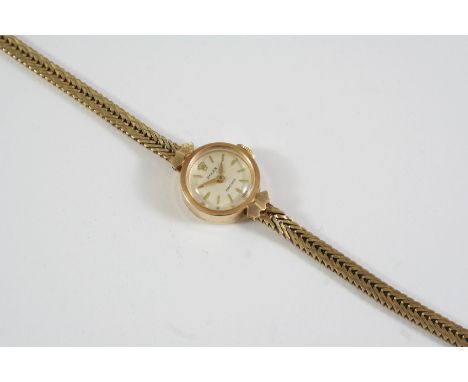 A LADY'S 9CT GOLD WRISTWATCH BY ROLEX the signed circular dial with dagger numerals, on a 9ct gold herringbone link bracelet 