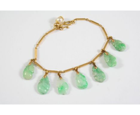 A JADE AND GOLD BRACELET the gold rectangular link bracelet suspends seven foliate carved sections of jade, 16cm long