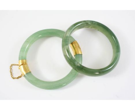 A MOTTLED GREEN JADE BANGLE together with another green jade bangle