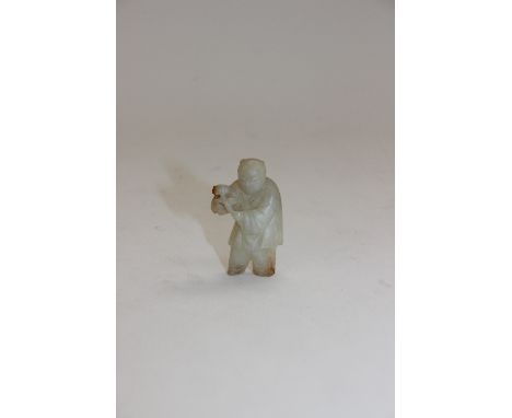 A small carved jade figure of a man with a branch, with russet inclusions, 4cm high