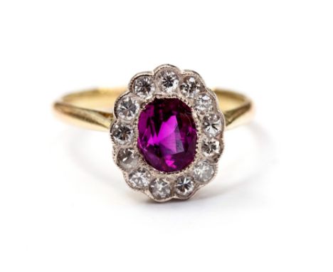 A ruby and diamond cluster ring, set with an oval-cut ruby, surrounded by thirteen diamonds, ring size M