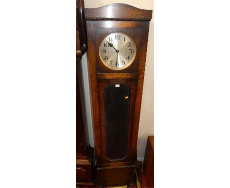 A 1930s oak longcase clock, having a silvered circular dial, glazed trunk door, with three train movement, pendulum and three