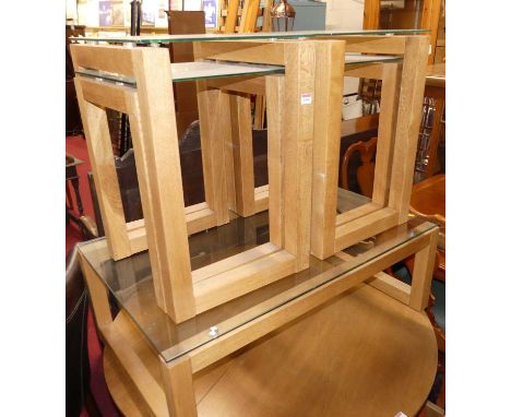 Two pairs of light oak and glass topped nests of two occasional tables, together with a matching coffee table (3)