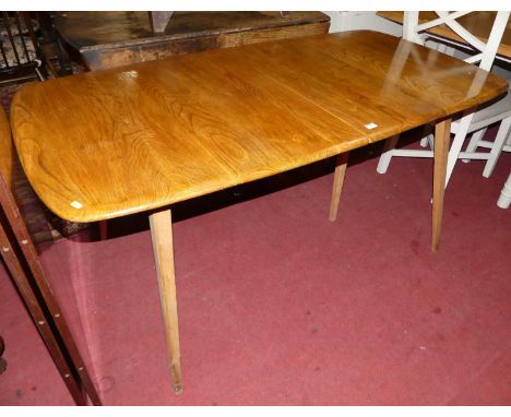 A 1960s Ercol elm extending dining table, having rounded corners, pull-out action and two extra drop-in leaves, raised on sli