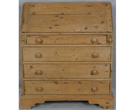 A 19th century pine bureau with fall front revealing a fitted interior above four long graduated drawers on shaped bracket fe