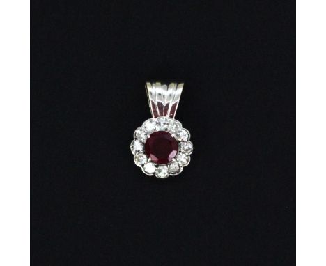 A white metal (tested minimum 14ct) cluster pendant set with a round cut ruby surrounded by diamonds, L. 1.5cm. Gross weight 
