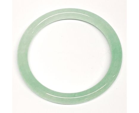 A polished pale green jade bangle, W. 8.5mm. Internal Dia. 6.2cm.