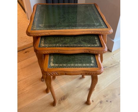 A carved light wood, leather topped nest of three tables with protective plate glass tops, 53 x 52cm.