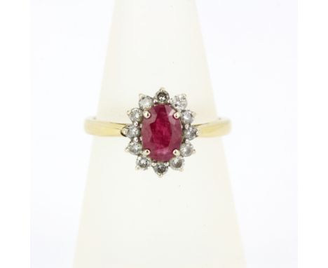 A yellow and white metal (tested minimum 9ct gold) ring set with an oval cut ruby surrounded by diamonds, (M).