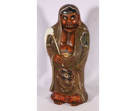 Large Japanese ceramic figure of Daruma, holding a fly whisk, with elaborate slip decorated robe, 45 cm. 