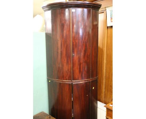 19th Century mahogany bow front standing corner cabinet raised on bun supports, 212 cm tall.