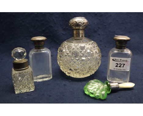 A group of five scent bottles to include; hobnail cut glass globular scent bottle with silver repousse top, a pair of pillar 