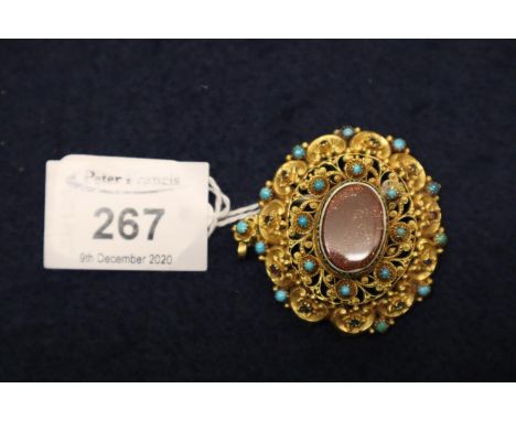 A yellow metal filigree brooch set with turquoise, ruby and goldstone.  Approximate weight 13.4 grams. 