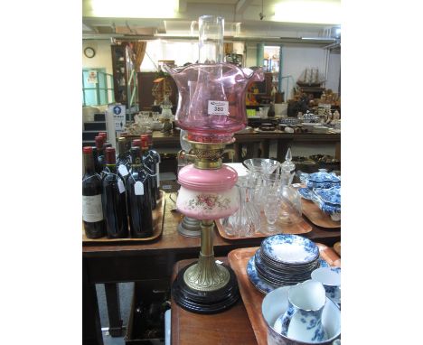 Early 20th Century double oil burner having cranberry glass shade, clear glass chimney above a ceramic floral reservoir on a 