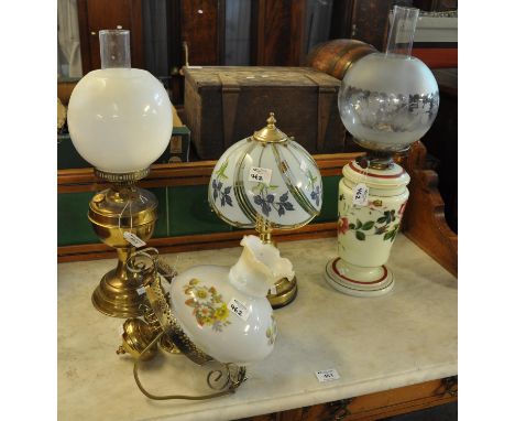 Two early 20th century double oil burner lamps, one with opaline glass reservoir, together with a modern brass and glass tabl