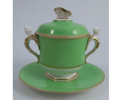 A Spode porcelain covered cup and stand, decorated with an apple green ground, a butterfly finial and a pair of handles mould