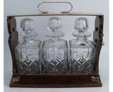 A Betjemann's Patent walnut three bottle tantalus, with silver plated hinged top and mounts, with small plaque engraved Lloyd