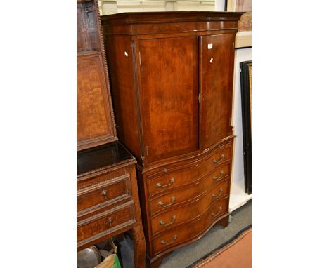 Mahogany serpentine cocktail cabinet, cavetto cornice, plain frieze, doors enclosing a glass shelf, base with slide above fou