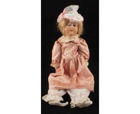 A German porcelain dressed doll marked CK 165/8 and a domed trunk containing a quantity of clothes and accessories