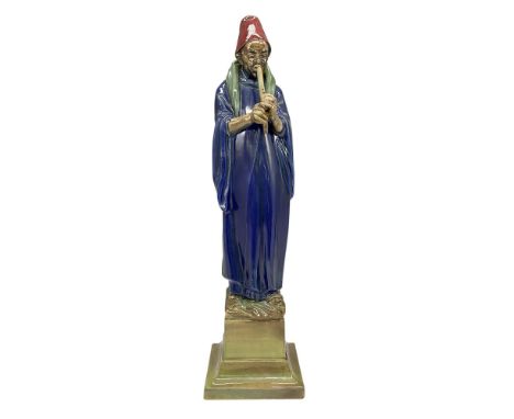 Charles Noke figure dressed in blue tunic with green scarf holding his flute. Figure is set on green base. Royal Doulton back