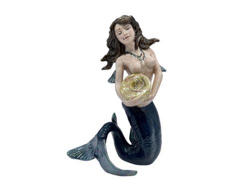 Rare luster porcelain figure of a mermaid in a dark sea-blue tail holding a large sun-yellow shell in her arms. Royal Doulton